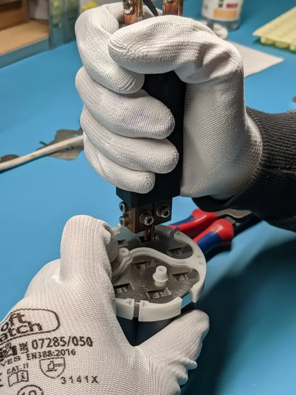 Služby hands holding battery cells with spot welder in right hand